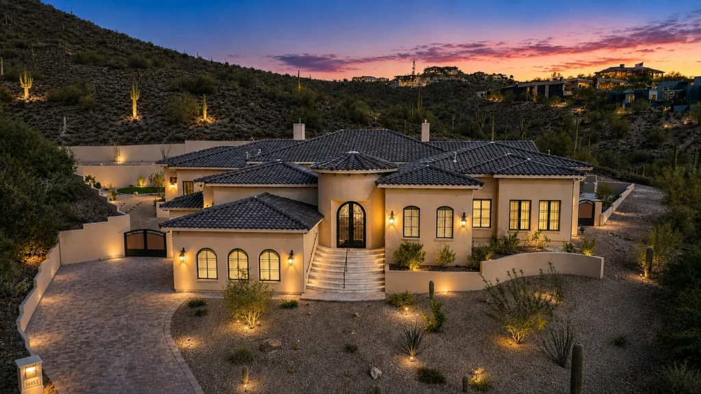 Elegant desert home illuminated at dusk, showcasing architectural design and surrounding landscape.